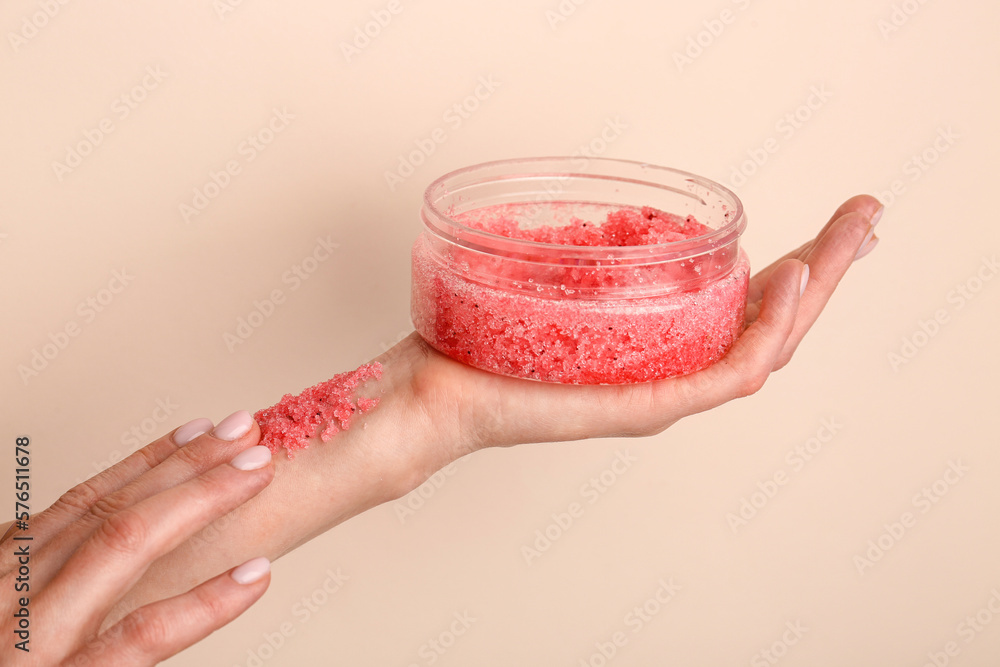 Female hands with jar of body scrub on color background, closeup