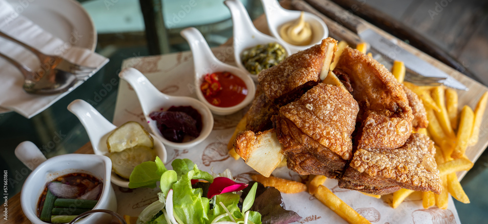 Eisbein with braised cabbage, salad and Yummy french fries with set of souces in bowl. Traditional O