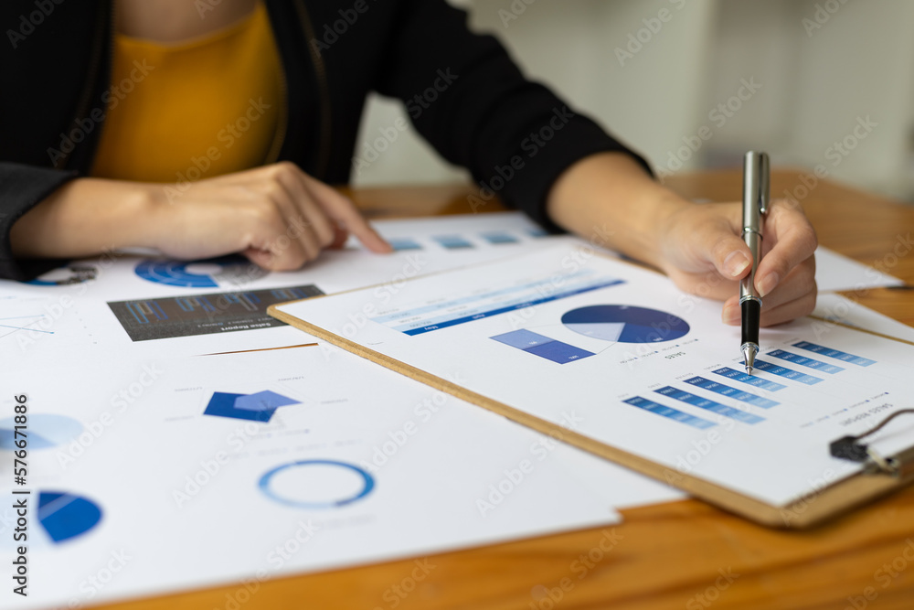 Businesswoman working with financial documents analyzing market growth report and company sales.