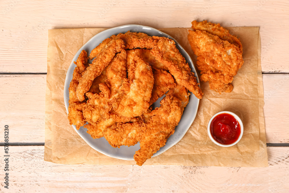 Plate with delicious nuggets and sauce on light wooden background