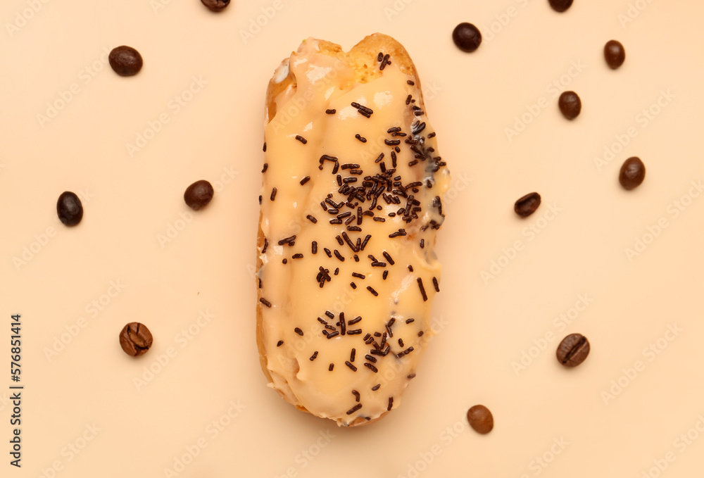 Delicious eclair and coffee beans on beige background