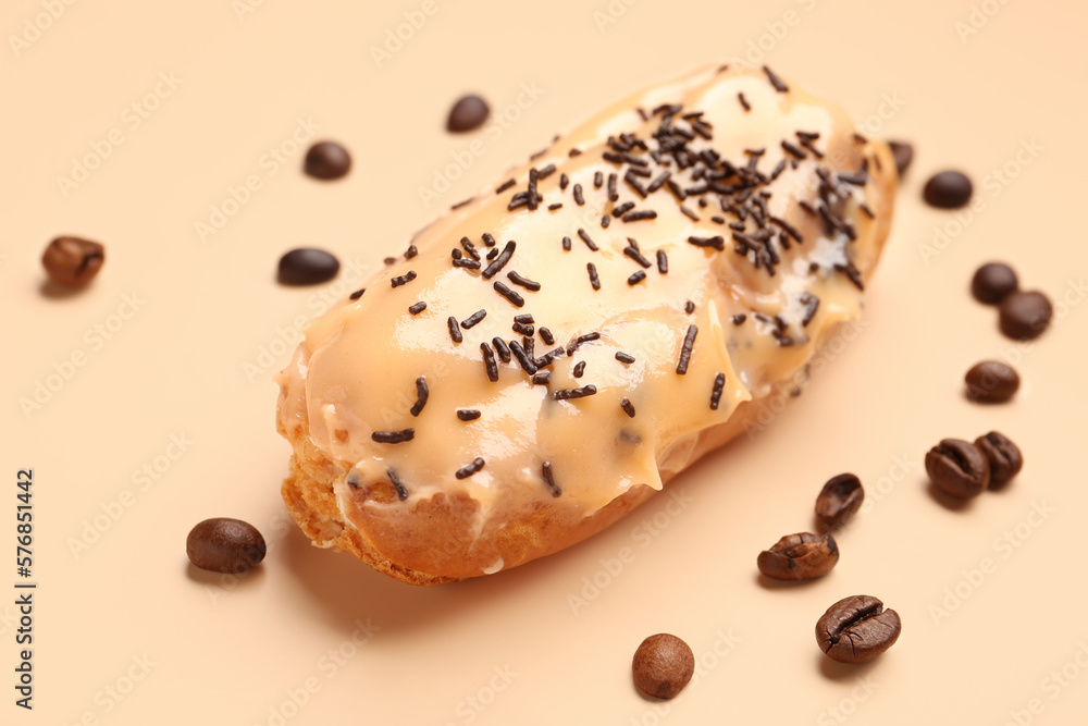 Delicious eclair and coffee beans on beige background