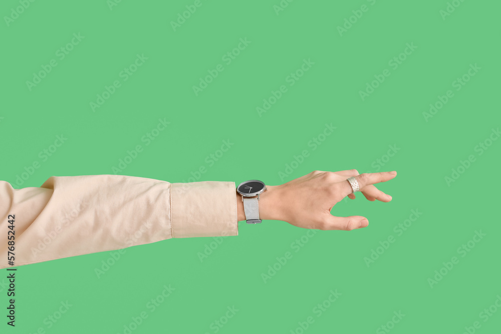 Woman with stylish wristwatch on green background