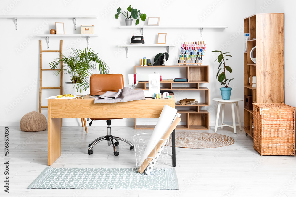 Interior of modern atelier with tailors workplace and shelving units