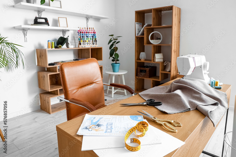 Interior of modern atelier with tailors workplace and shelving units