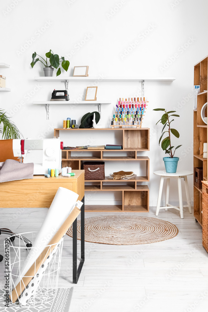 Interior of modern atelier with tailors workplace and shelving units