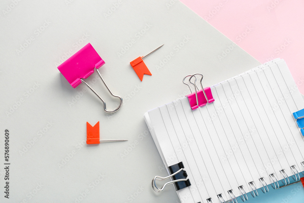 Notebook with binder clips and pins on paper sheets, closeup