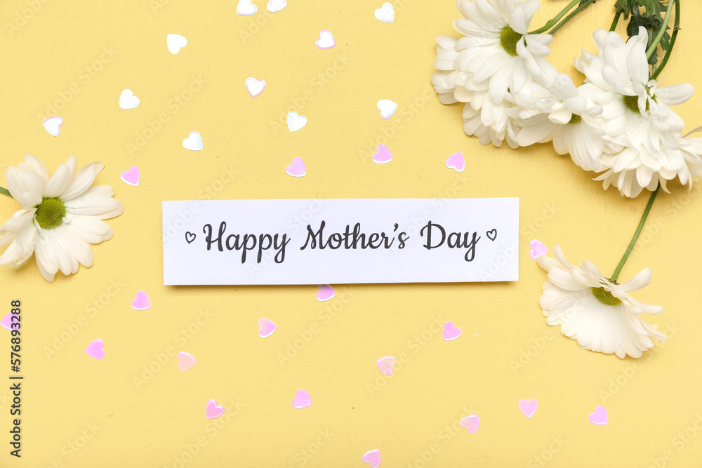 Paper with text HAPPY MOTHERS DAY, sequins and chamomile flowers on yellow background