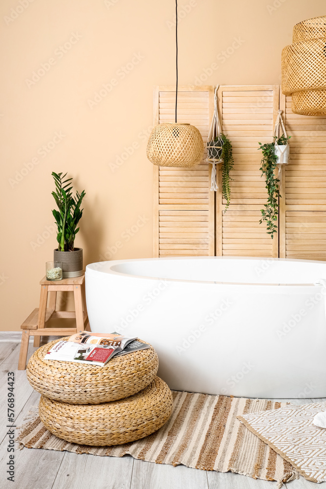 Interior of bathroom with bathtub, houseplants and folding screen