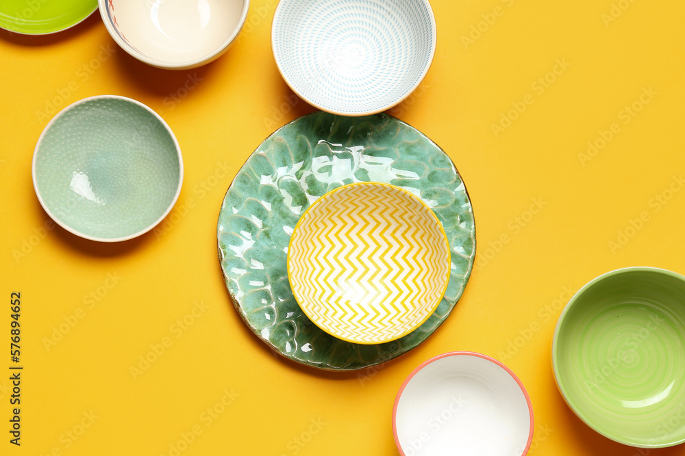 Composition with clean ceramic plates and bowls on orange background