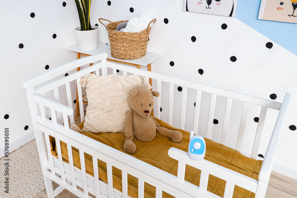 Crib with toy bear and baby monitor in childrens bedroom