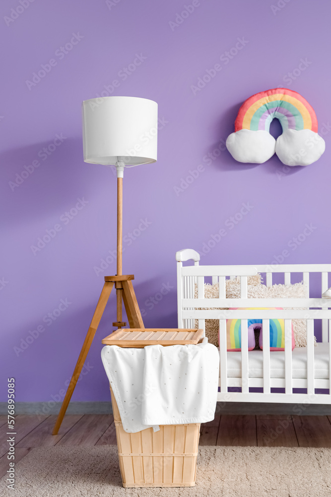 Interior of childrens bedroom with crib, basket and lamp