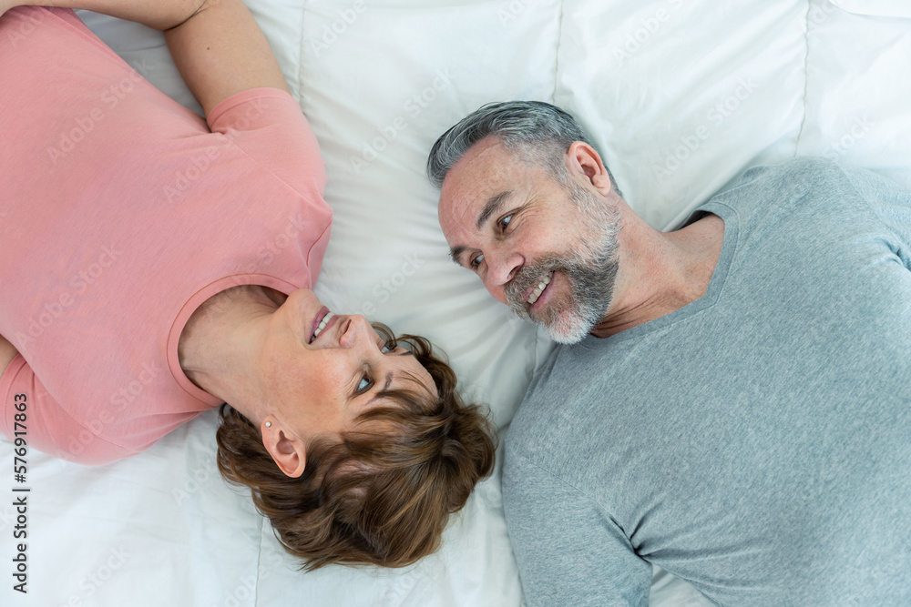 Caucasian senior older couple lying down on bed then look at each other. 