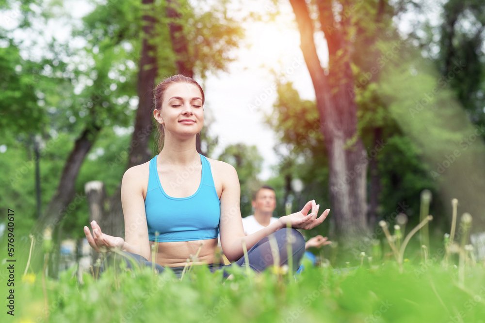 Girl meditates in lotus pose on green grass