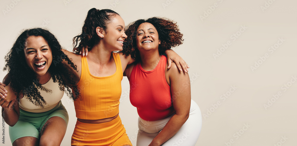 Fun in fitness clothing: Three female friends laughing happily in a sports studio