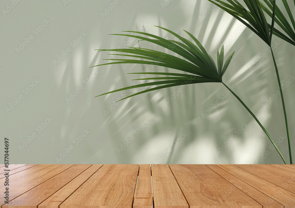 Empty wooden table counter with tropical palm tree in dappled sunlight, leaf shadow on green wall fo