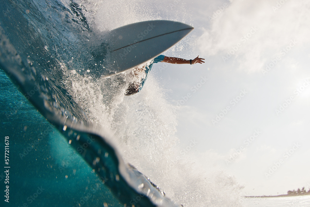 Surfer rides the wave. Young man surfs the ocean wave in the Maldives