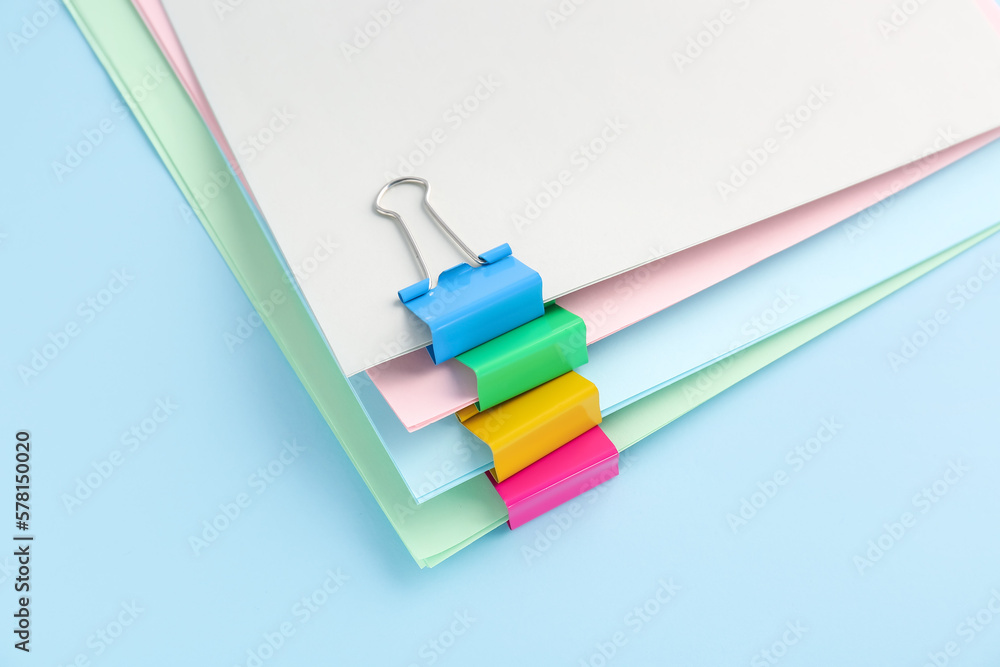 Paper sheets with binder clips on color background, closeup