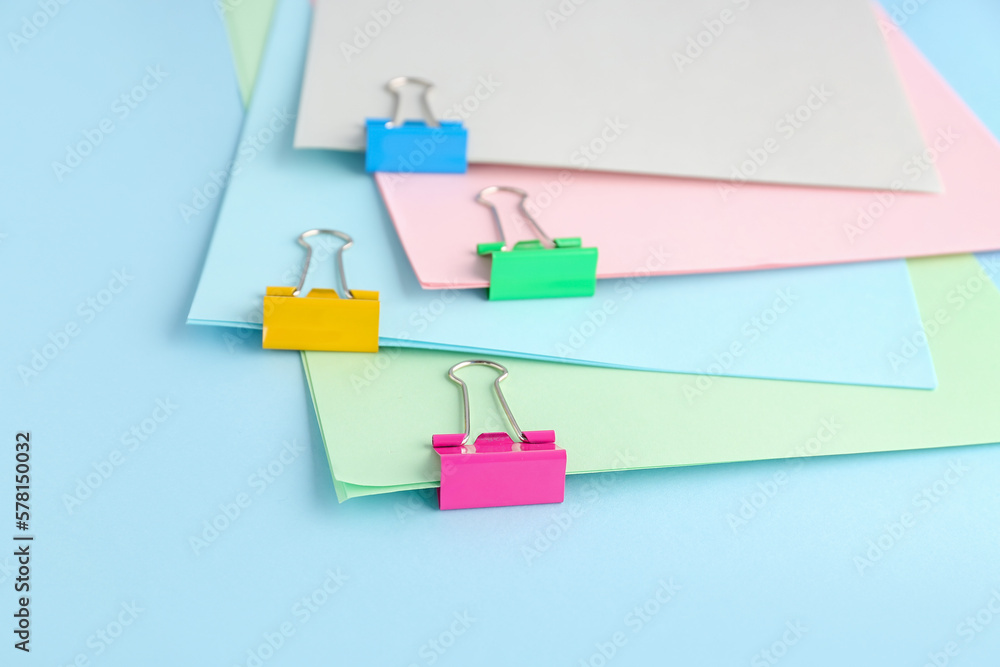 Paper sheets with binder clips on color background, closeup