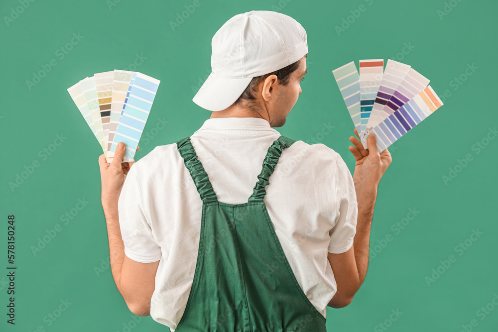 Male painter with color palettes on green background, back view