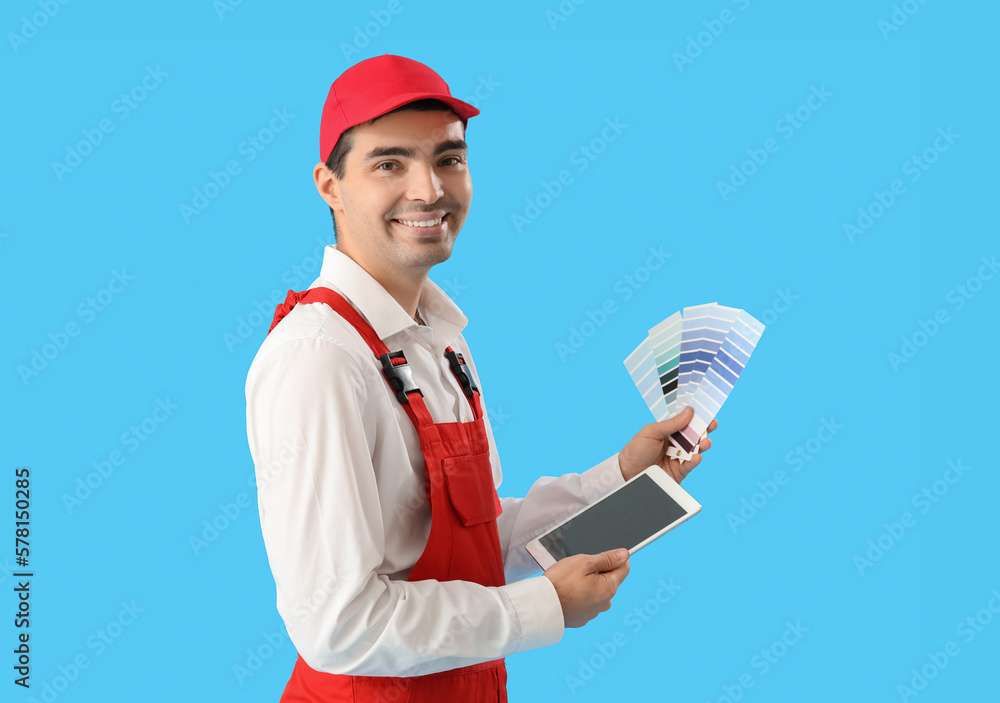 Male painter with color palettes and tablet computer on blue background