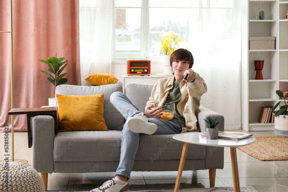 Teenage boy with chips watching TV at home