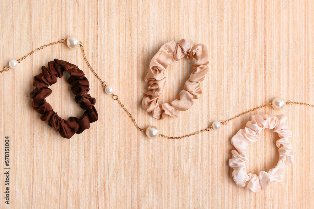 Scrunchies and beautiful necklace on wooden background