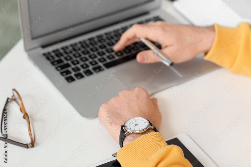 Young man with watch working on laptop, closeup