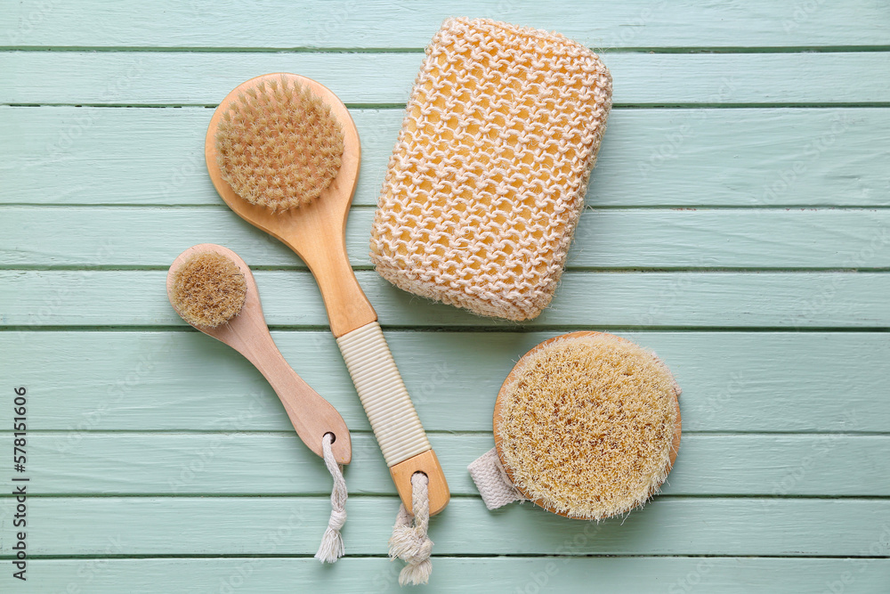 Massage brushes and bath sponge on color wooden background