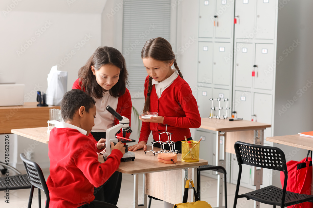 Little children with microscope having Chemistry lesson in science classroom