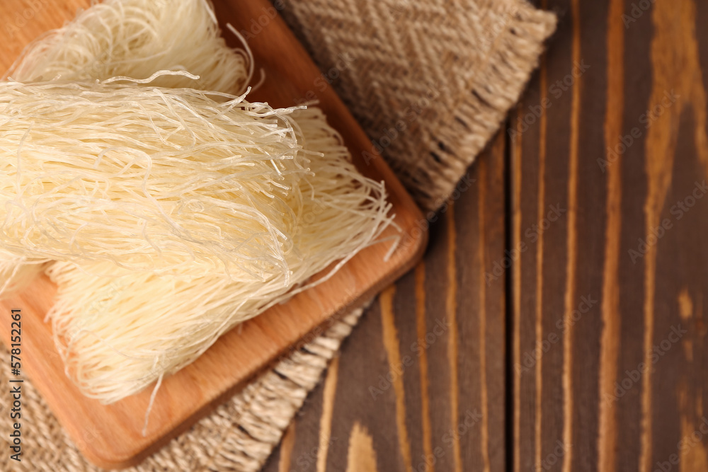 Board with raw rice noodles on wooden table