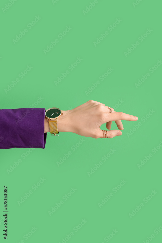 Woman with golden wristwatch on green background