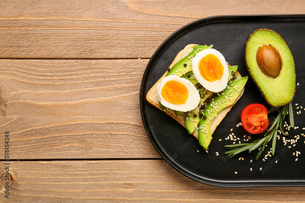 Plate with delicious avocado toast and boiled egg on brown wooden background