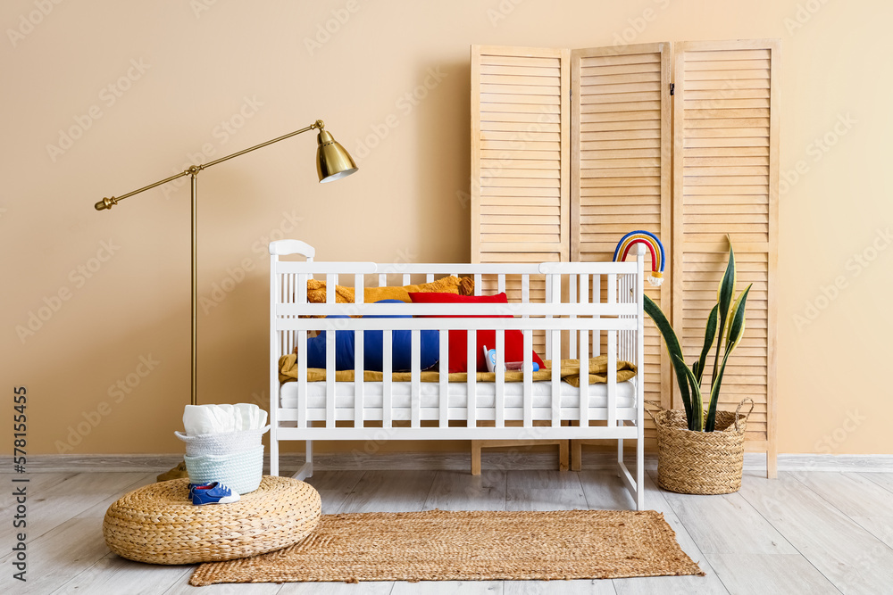 Interior of childrens bedroom with crib, lamp and folding screen