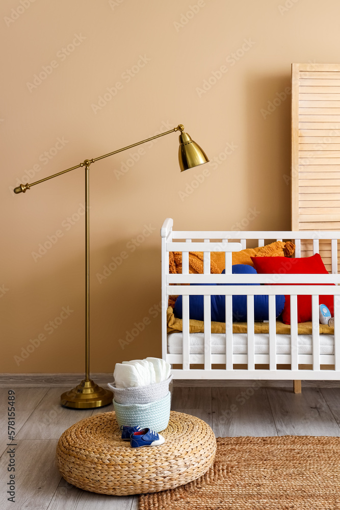 Interior of childrens bedroom with crib, pouf and lamp