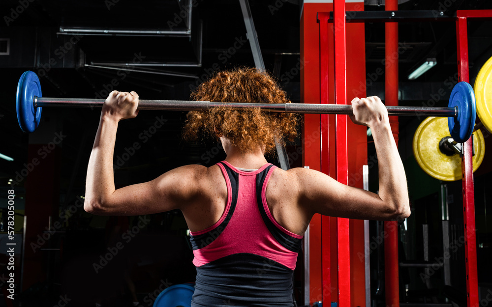 Woman bodybuilder engaged with a barbell in the gym