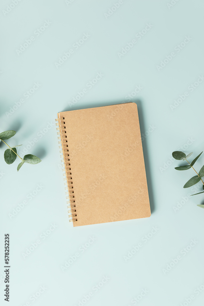 Notebook and flowers on blue background. Flat lay top view copy space mockup