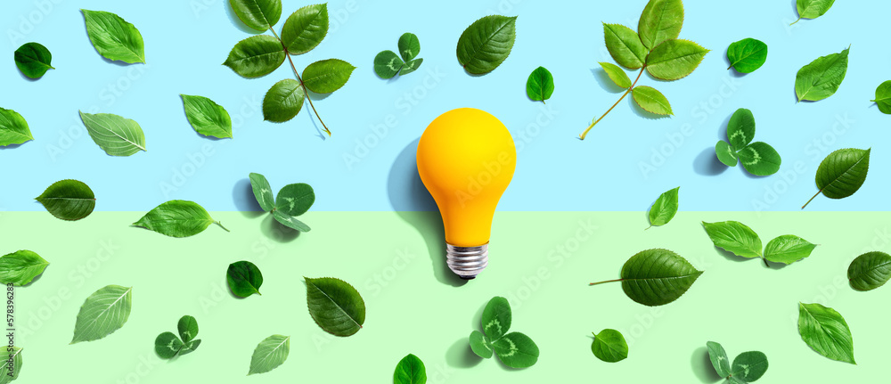 Yellow light bulb with green leaves - Flat lay