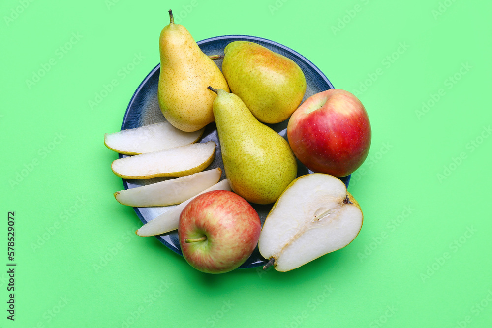 Plate with fresh pears and apples on color background