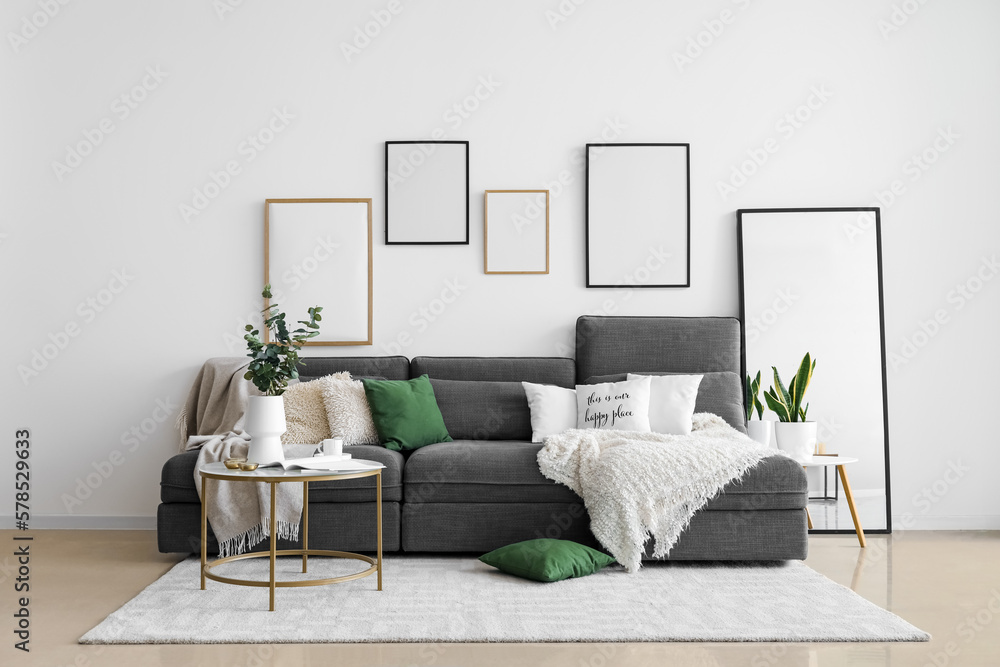 Interior of living room with black sofa, tables and blank frames