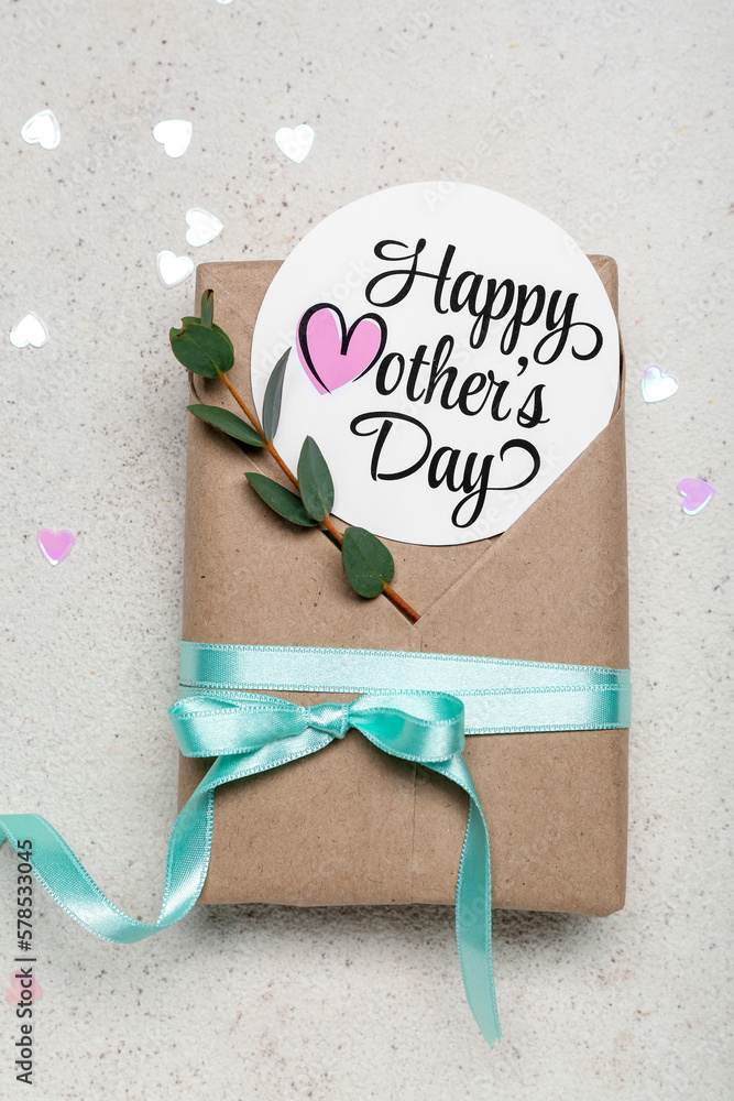 Card with text HAPPY MOTHERS DAY and beautiful gift box on light background