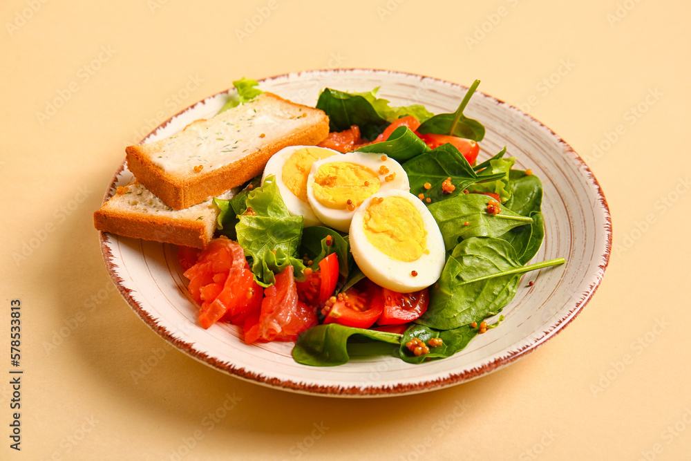 Plate of delicious salad with boiled eggs and salmon on beige background