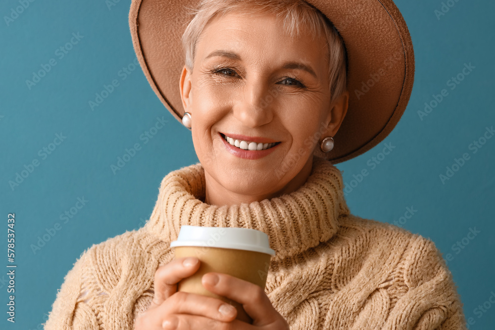 Beautiful mature woman with cup of coffee on blue background, closeup