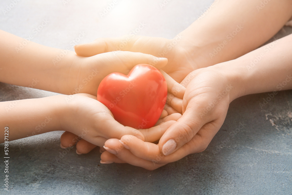 Hands of woman and child with red heart, closeup. Mothers Day