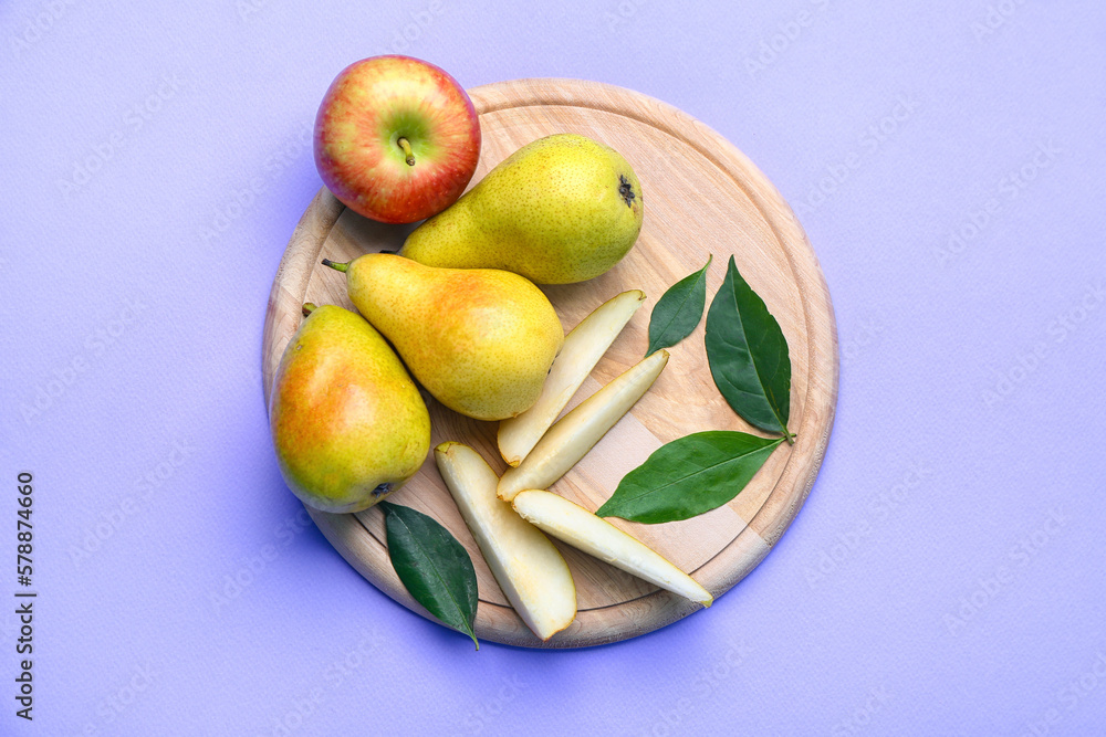 Wooden board with fresh pears and apple on lilac background