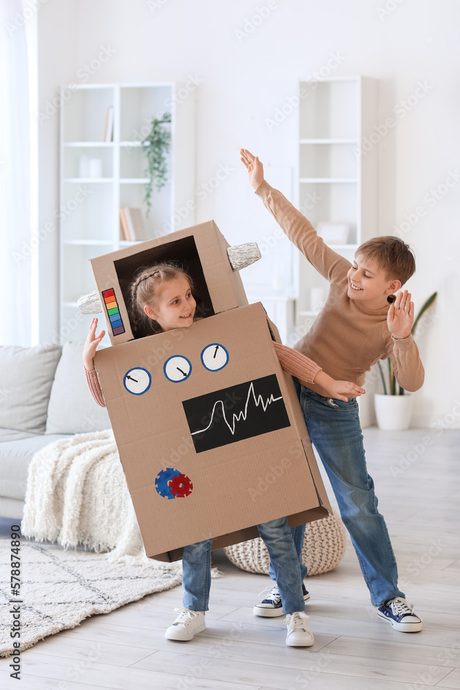 Little girl in cardboard robot costume playing with her brother at home