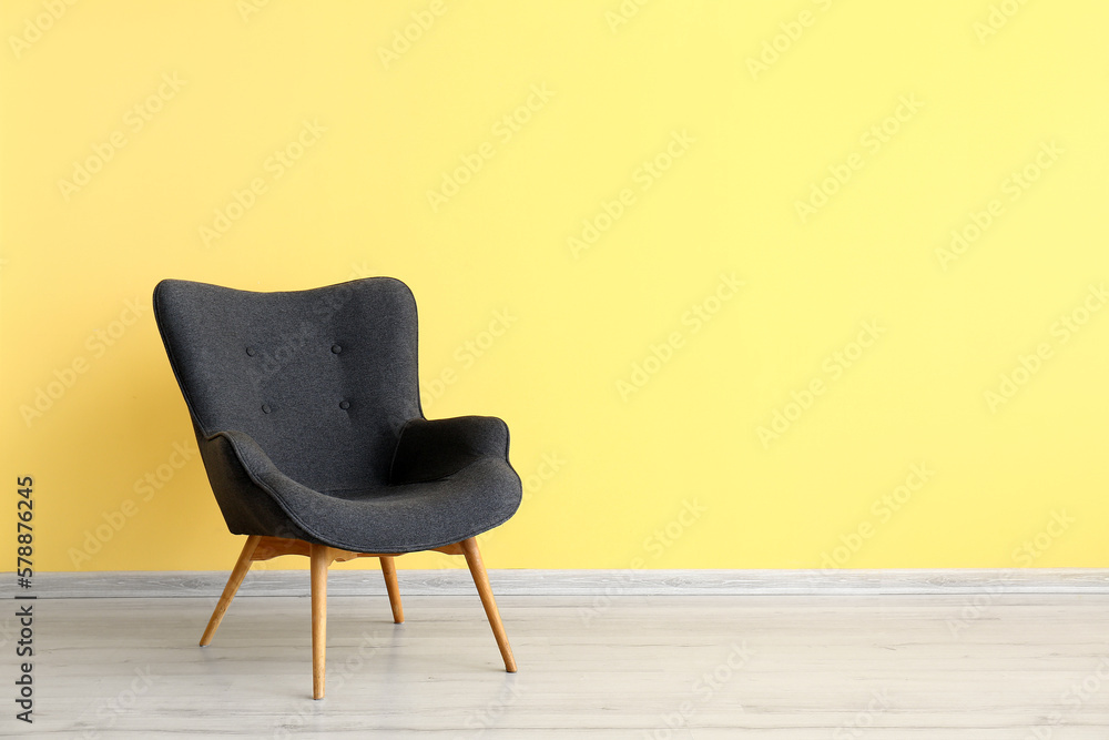 Stylish grey armchair near yellow wall