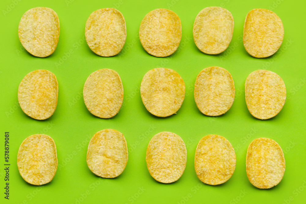 Many delicious potato chips on green background