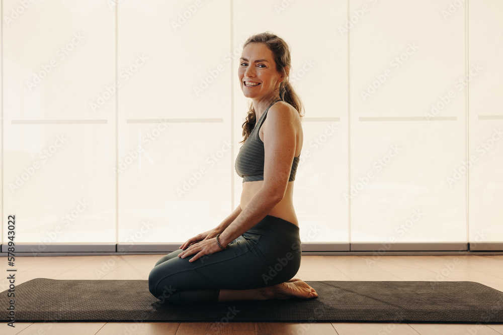 Happy elderly woman smiling while kneeling in thunderbolt pose