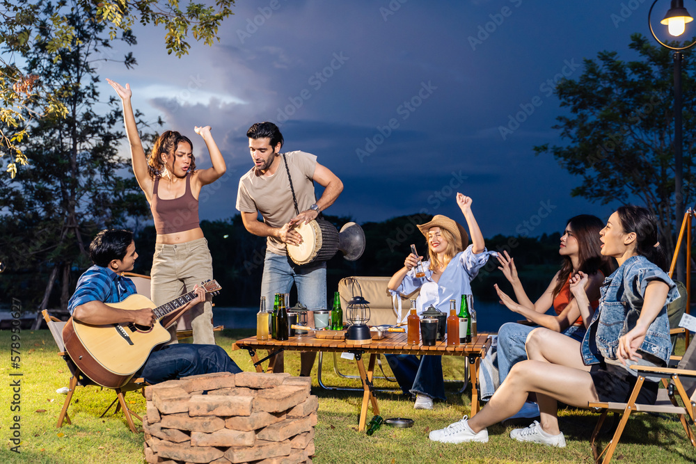 Group of diverse friend having outdoors camping party together in tent.